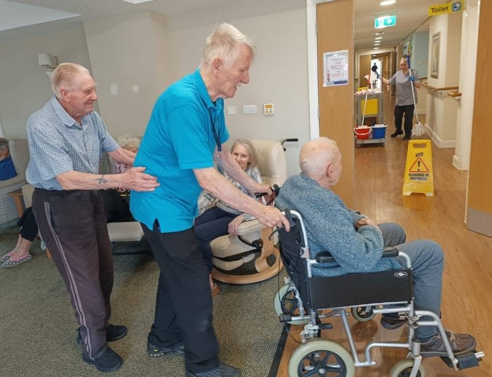 older people pushing a man in a wheelchair